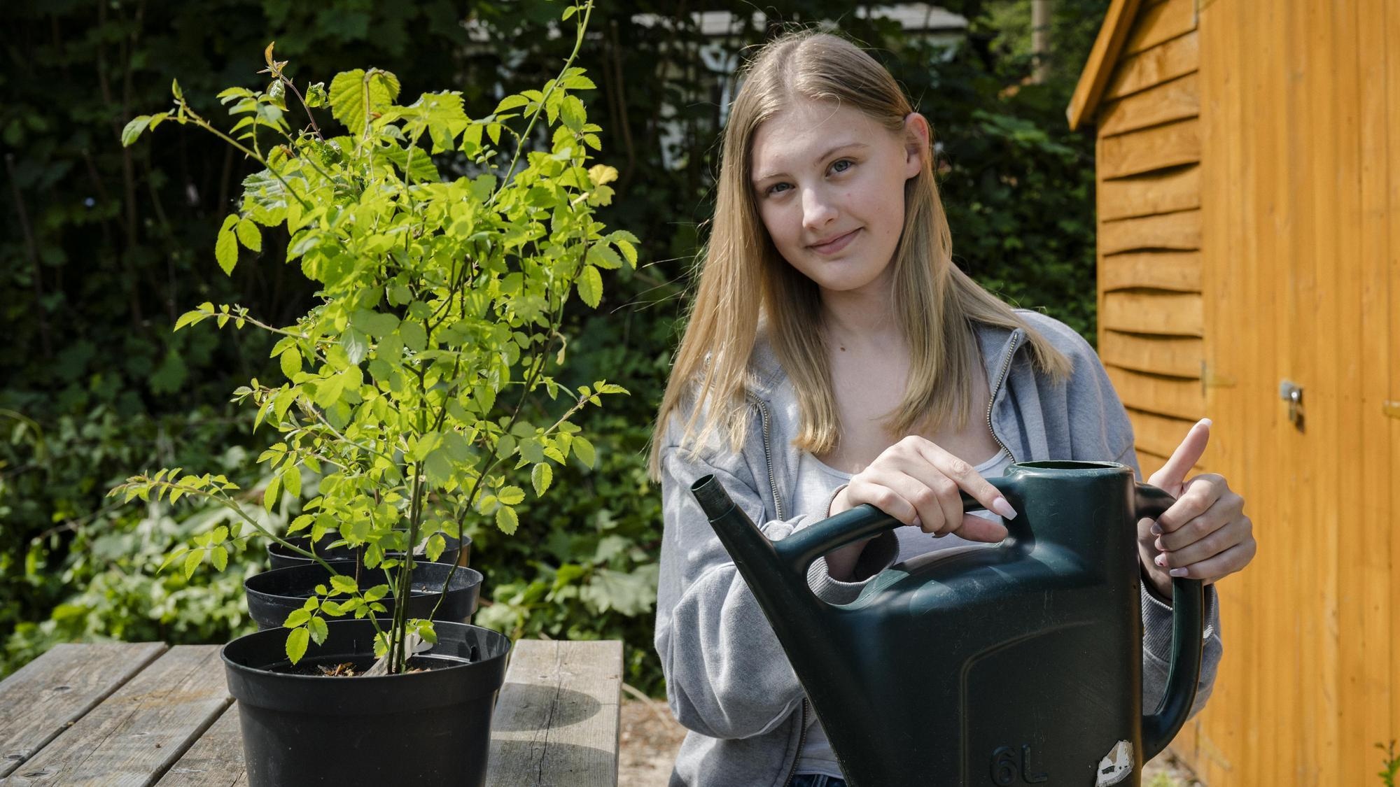 Student sitting outside watering a plant in the fresh air