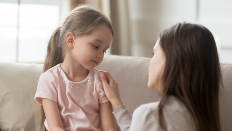 girl sitting on sofa with mum next to her talking calmly