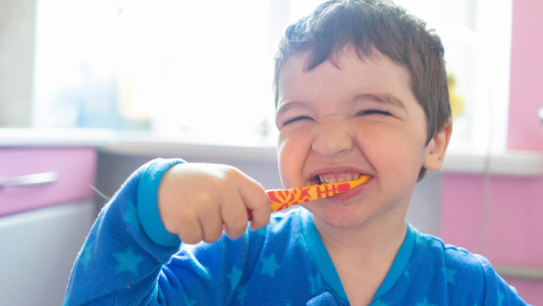 boy brushing his teeth in the bathroom and looking happy