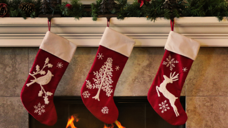 three red stockings, handing on the mantle, in front of a lit fire