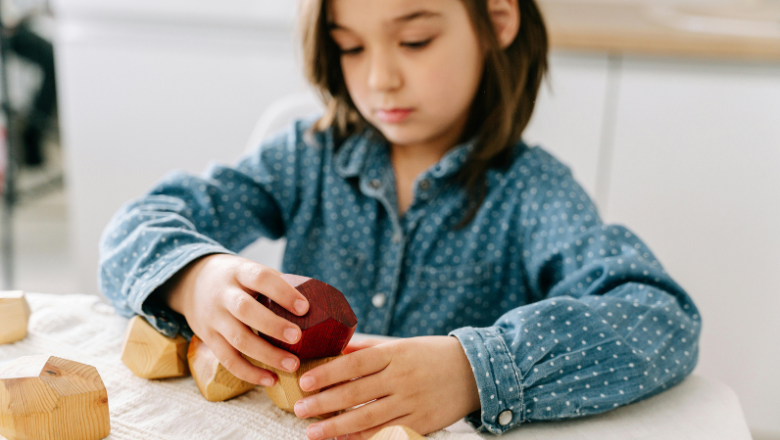 girl playing with stackable wooden blocks at a table