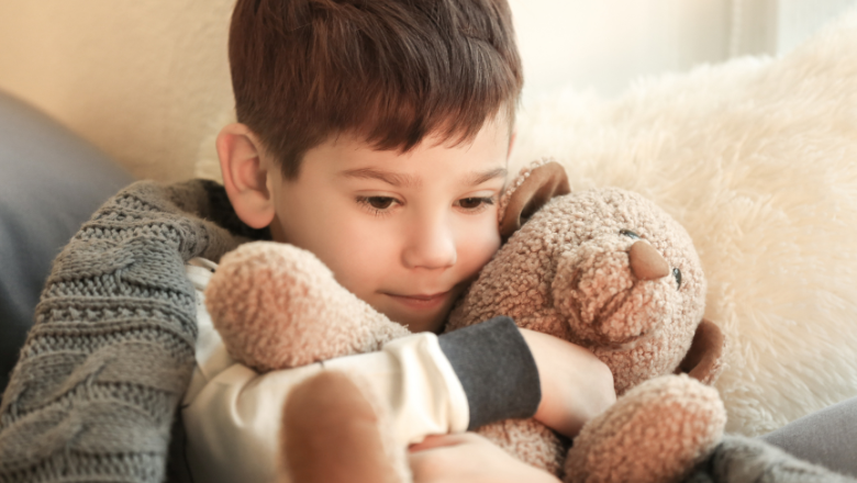 a boy hugging a beige teddy bear in a moment of calm